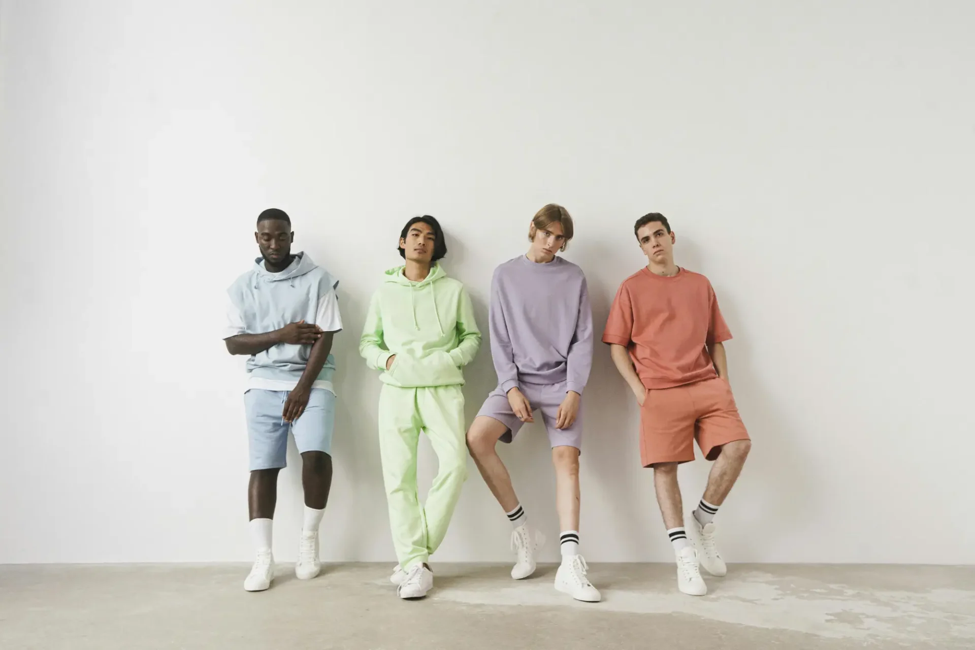 Four young men in different colors and styles of clothing.