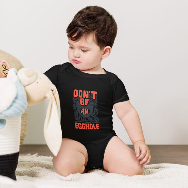 A baby in black shirt playing with stuffed animal.