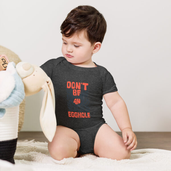 A baby in a onesie playing with a teddy bear