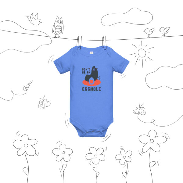 A blue onesie hanging on a line with flowers and birds.