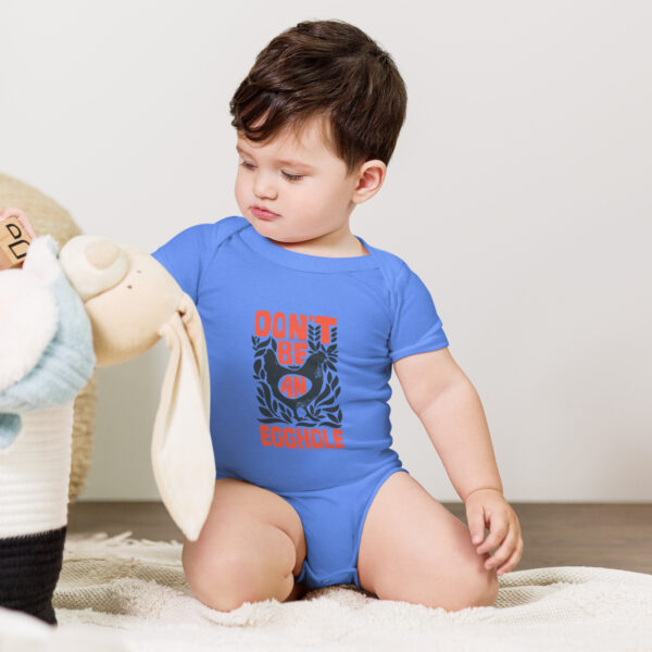 A baby sitting on the ground playing with a teddy bear.