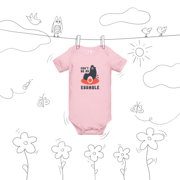 A pink onesie hanging on a line with flowers and bees.