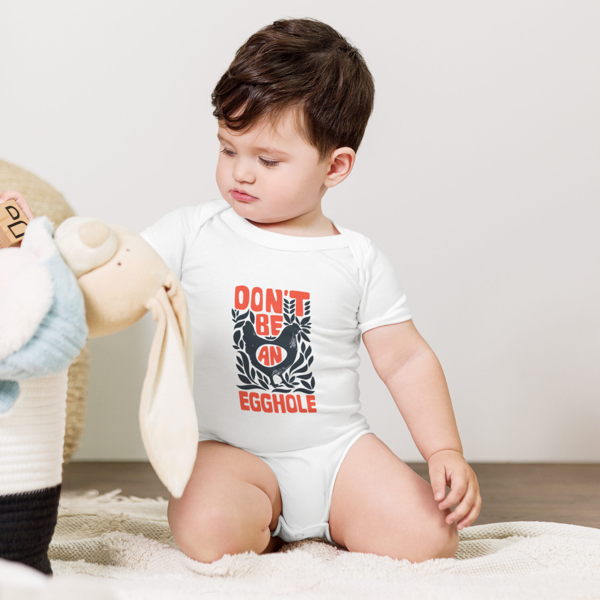 A baby sitting on the ground playing with a teddy bear.