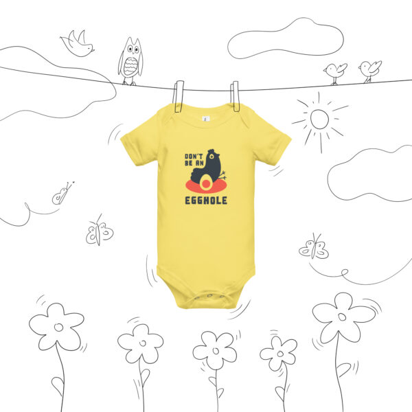 A yellow onesie hanging on a line with drawings of flowers and bees.