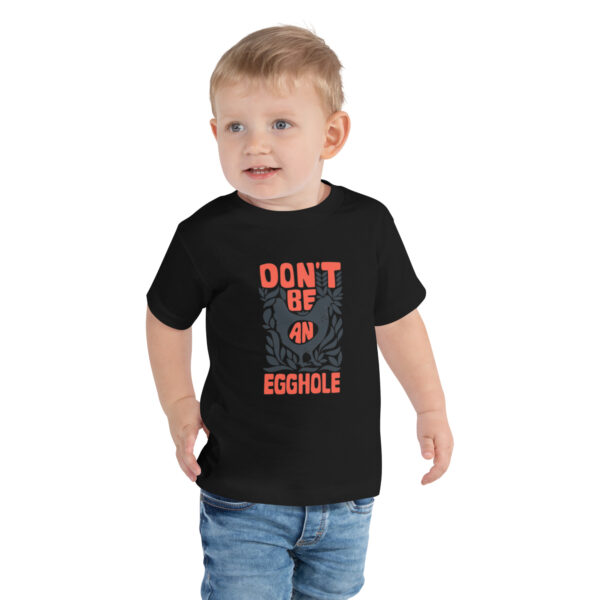 A toddler wearing a t-shirt with the words don 't be an asshole.