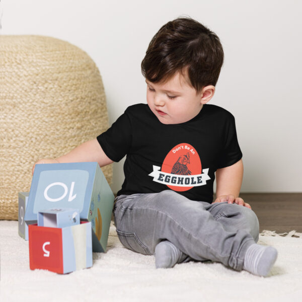 A toddler playing with a toy house on the floor