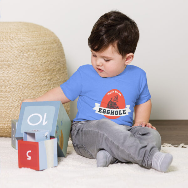 A toddler playing with a toy house on the floor