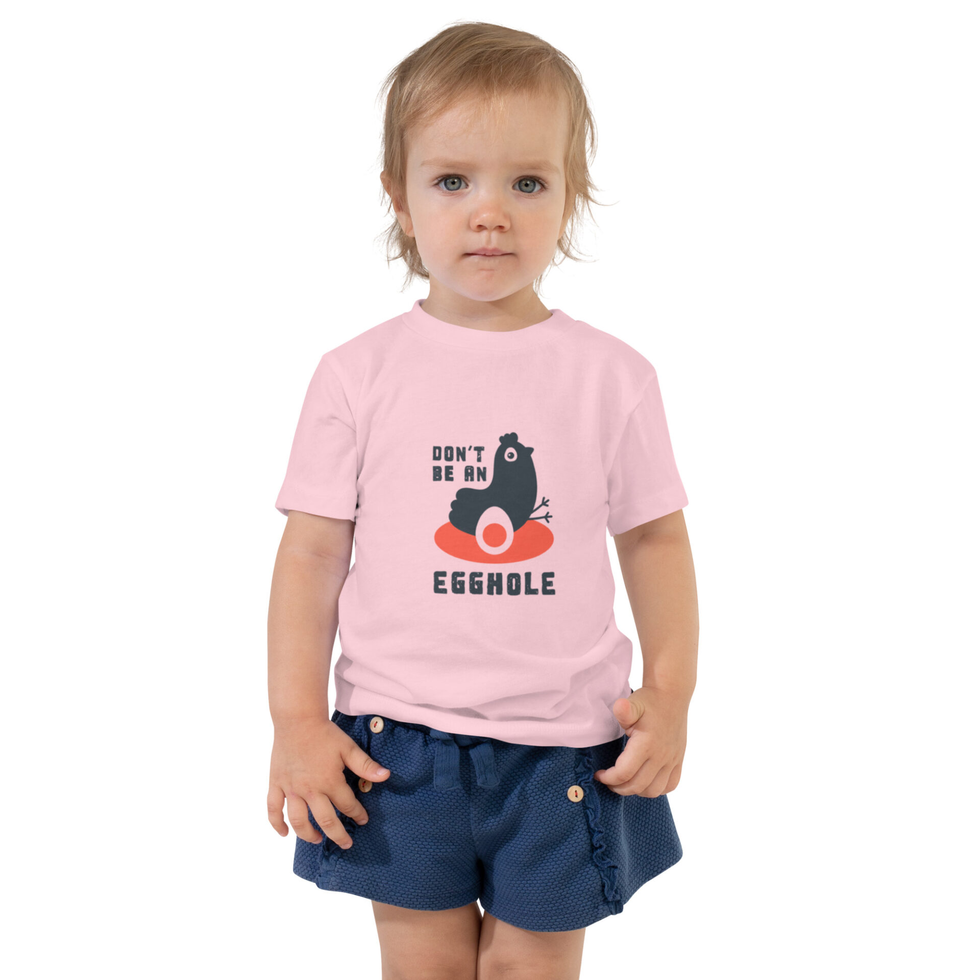 A toddler wearing a pink shirt and blue shorts.