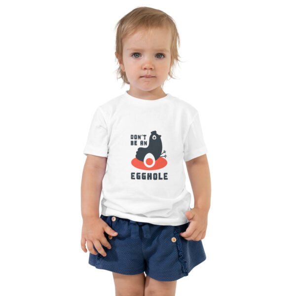 A toddler wearing a white t-shirt and blue shorts.