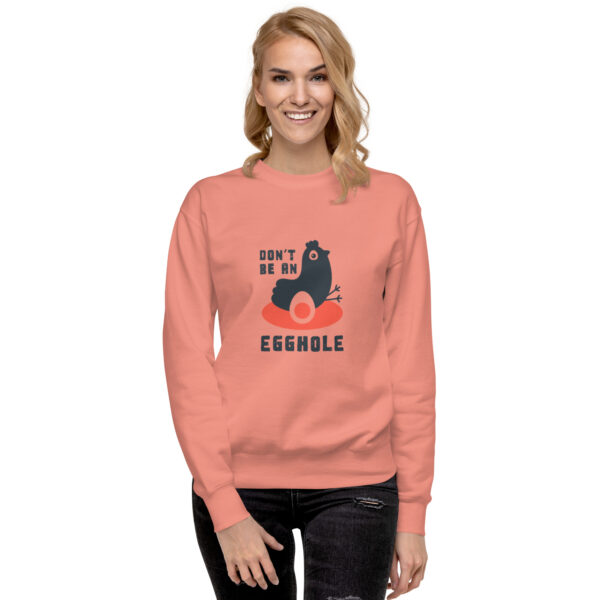 A woman wearing an orange sweatshirt with a black cat on it.