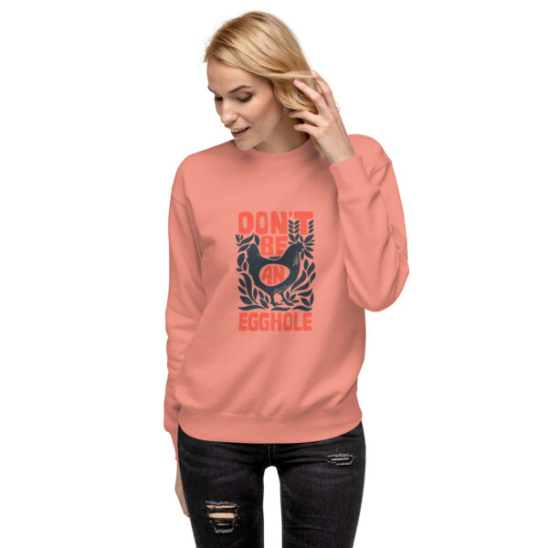 A woman wearing an orange sweatshirt with a rooster on it.