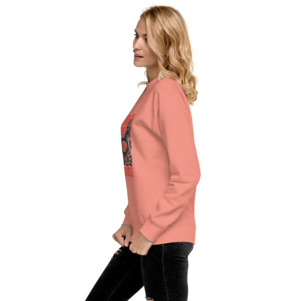 A woman in pink sweatshirt standing next to a wall.