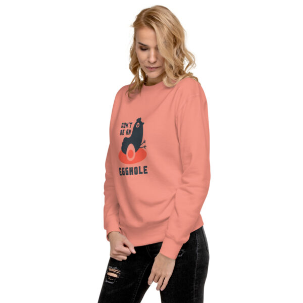 A woman wearing an orange sweatshirt with a cat on it.