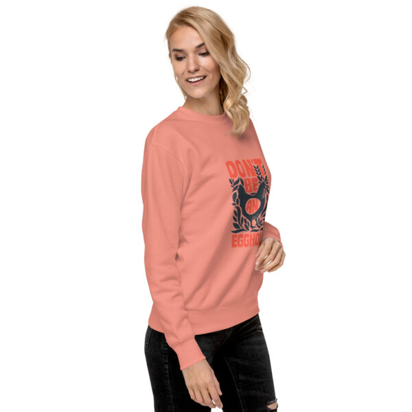 A woman wearing an orange sweatshirt with a cat on it.