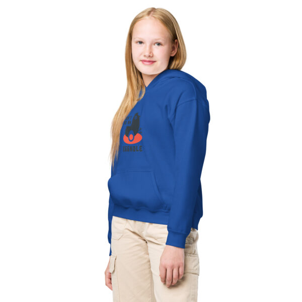 A girl wearing a blue hoodie with an orange and black sailboat on it.