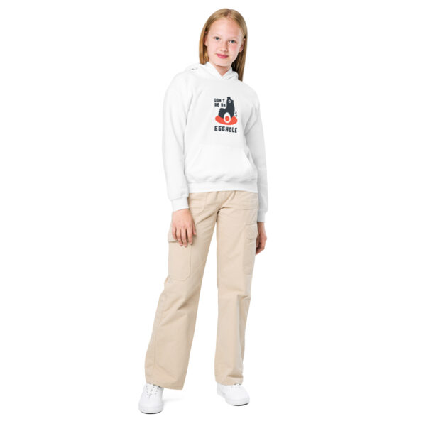 A girl standing in front of the camera wearing white pants and a sweatshirt.