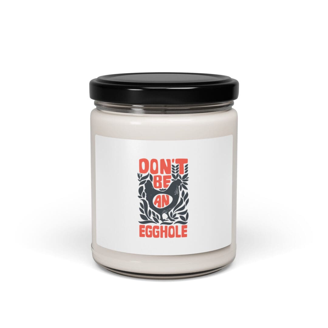 White candle in a glass jar with a black lid and a humorous label.