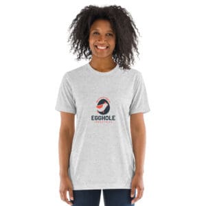 Smiling woman wearing a light gray t-shirt with a colorful circular logo and text.