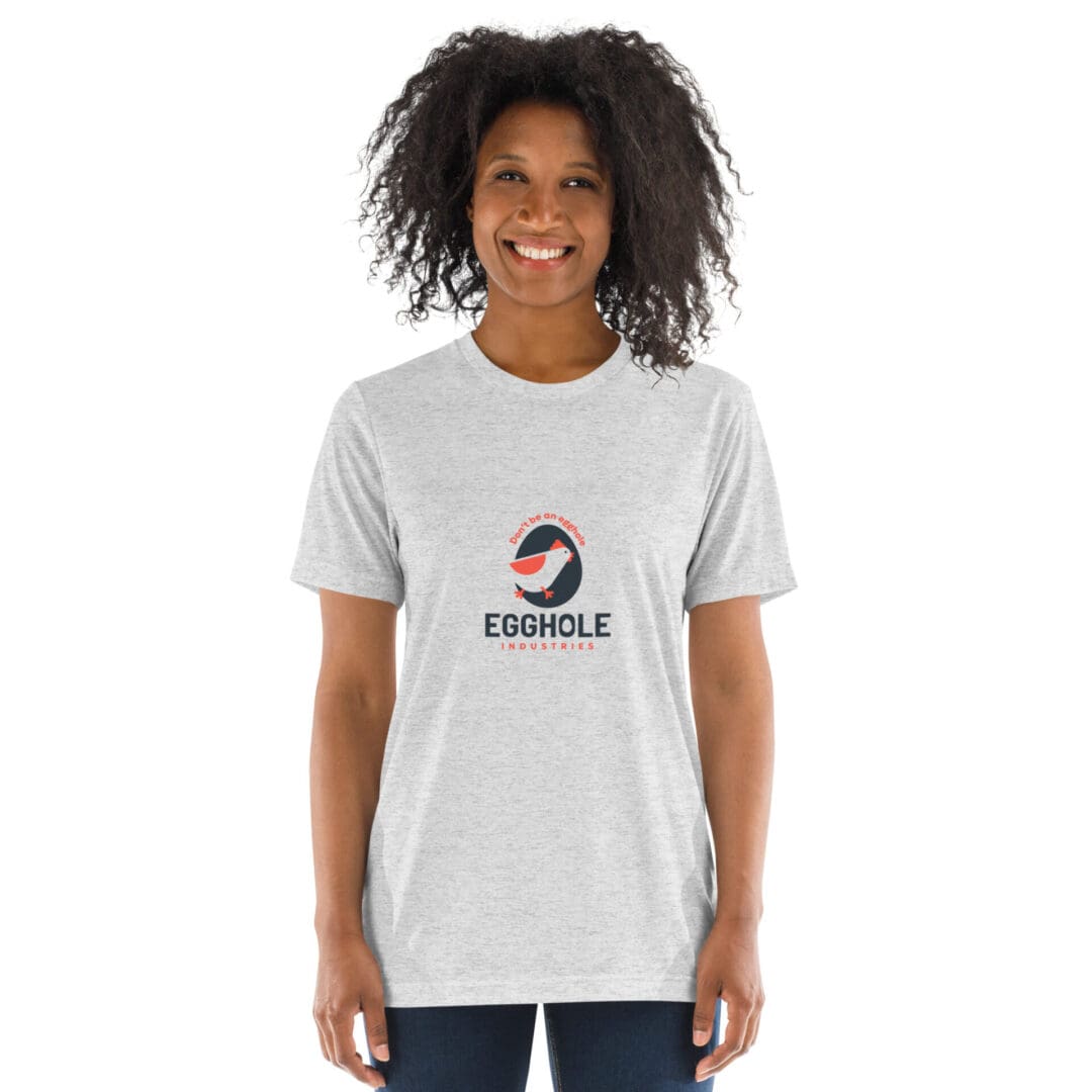 Smiling woman wearing a light gray t-shirt with a colorful circular logo and text.